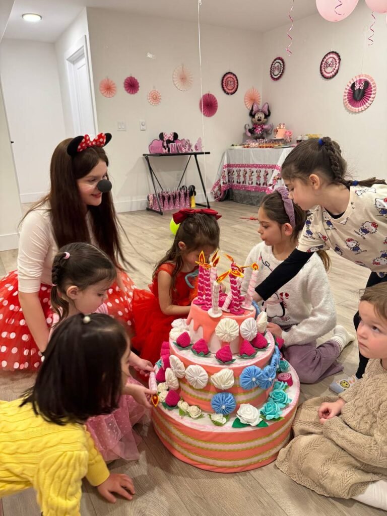 hildren celebrating a birthday with a colourful themed cake
