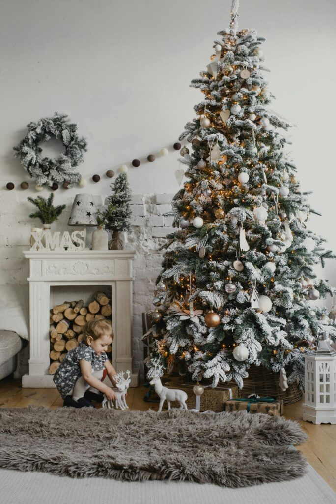 Charming indoor Christmas scene with a decorated tree and child by a cozy fireplace.