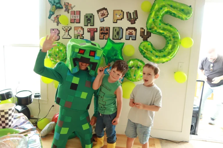 Green Minecraft posing with children at a kids birthday party